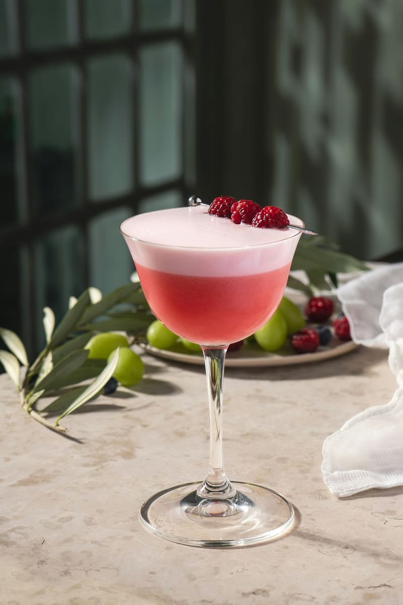 a pink cocktail with raspberries