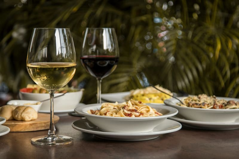 wine glasses beside a plate of pasta