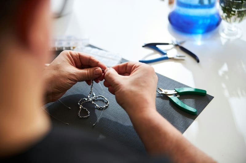 hands working on a silver necklace