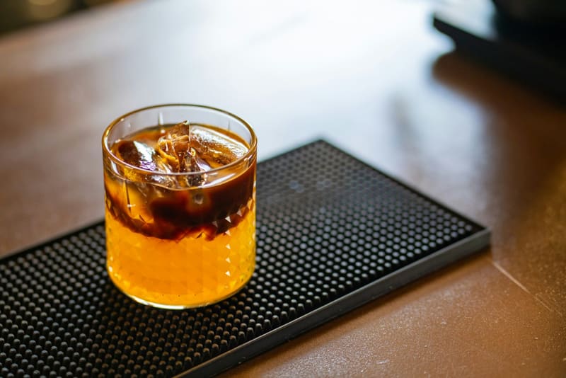 a layered cocktail on a bar mat