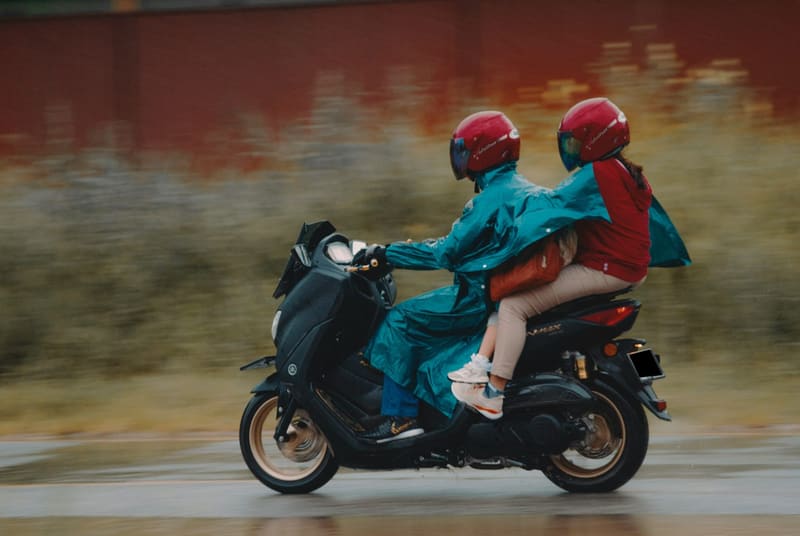 two riders on a scooter in the rain