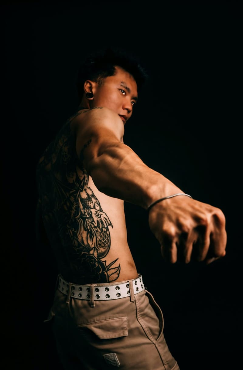 a tattooed torso and arm in low light