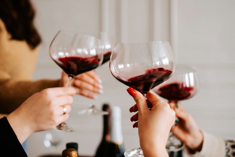 two burgundy glasses raised